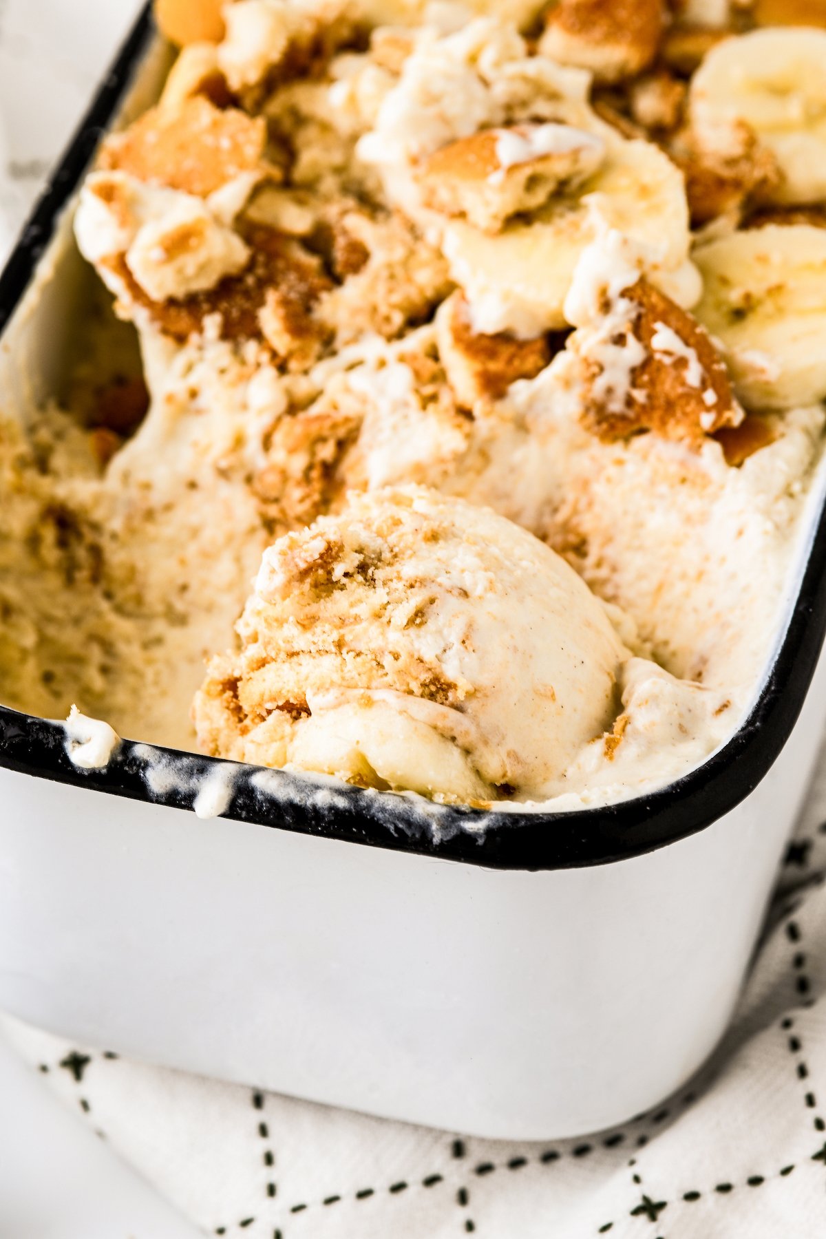 Close-up of creamy banana pudding ice cream with wafers in a metal tin.