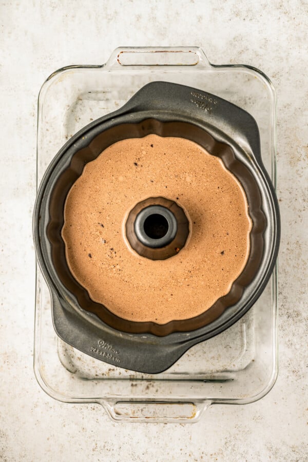 Bundt pan filled with batter in the water bath.