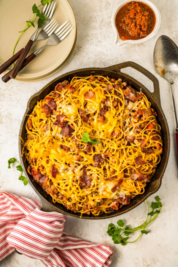 Cowboy spaghetti in a skillet topped with melty cheese.