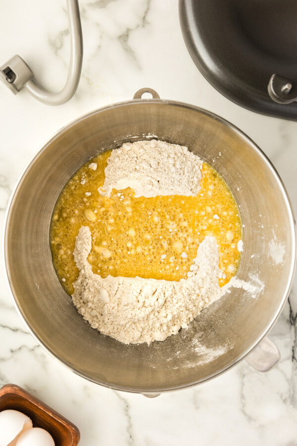 Butter, eggs, flour, yeast and more being mixed together in a mixing bowl.