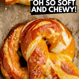 A soft pretzel on a cookie sheet brushed with melted butter and sprinkled with coarse salt.