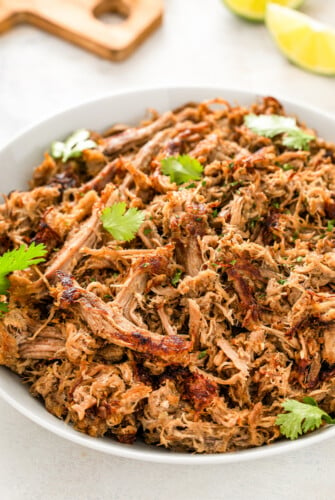 A bowl of juicy and crispy shredded instant pot carnitas topped with fresh cilantro.