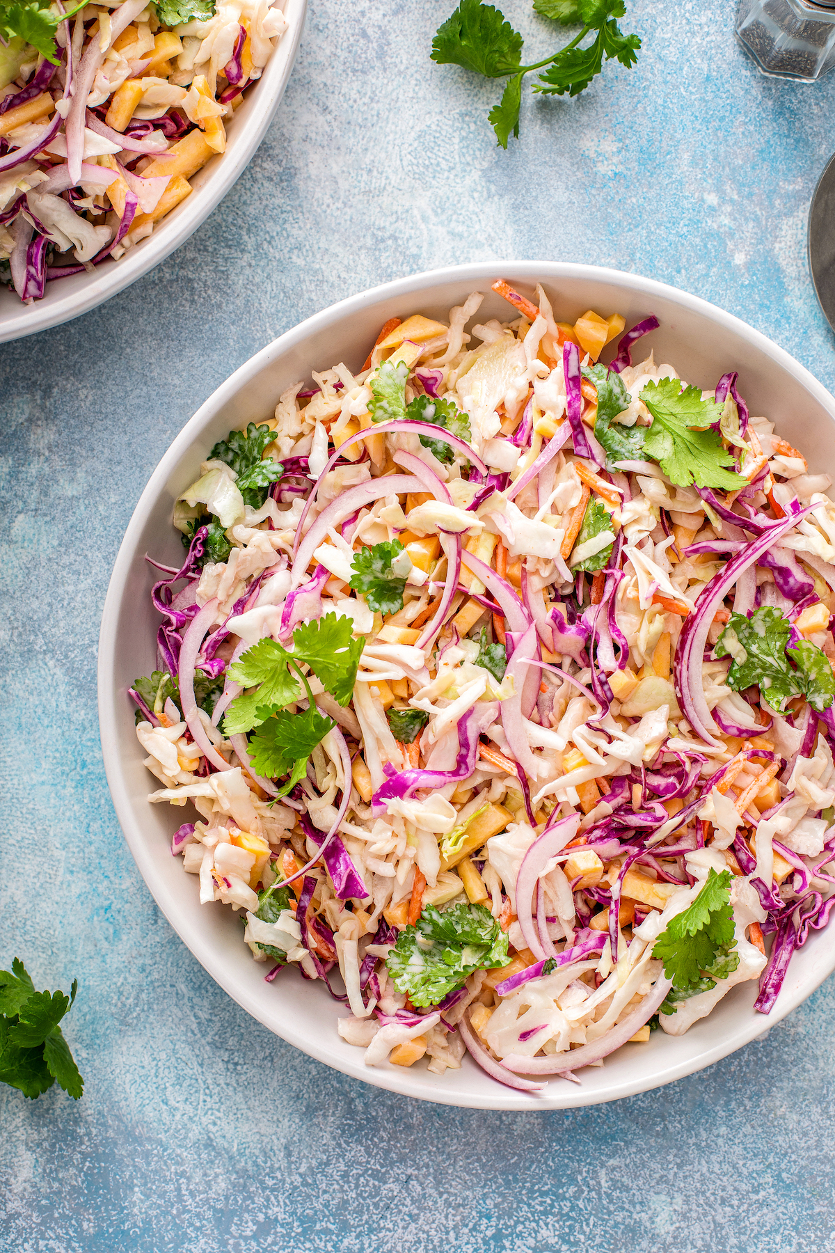 A bowl of fresh and creamy mango slaw with cilantro and red onion.