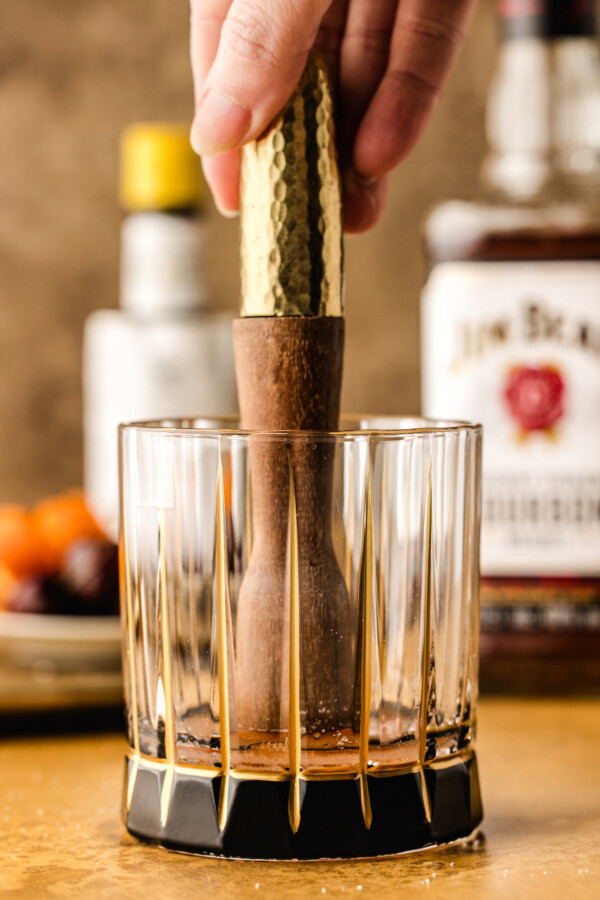 Mudding the sugar and bitters together in a short rocks glass.