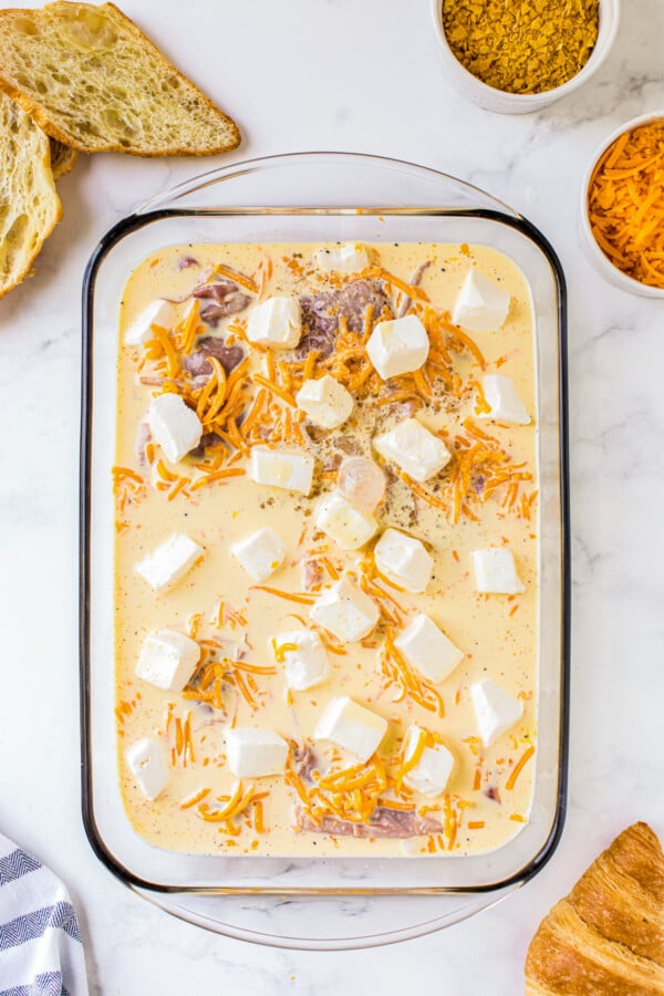 Cubes of cream cheese spread on top of casserole.