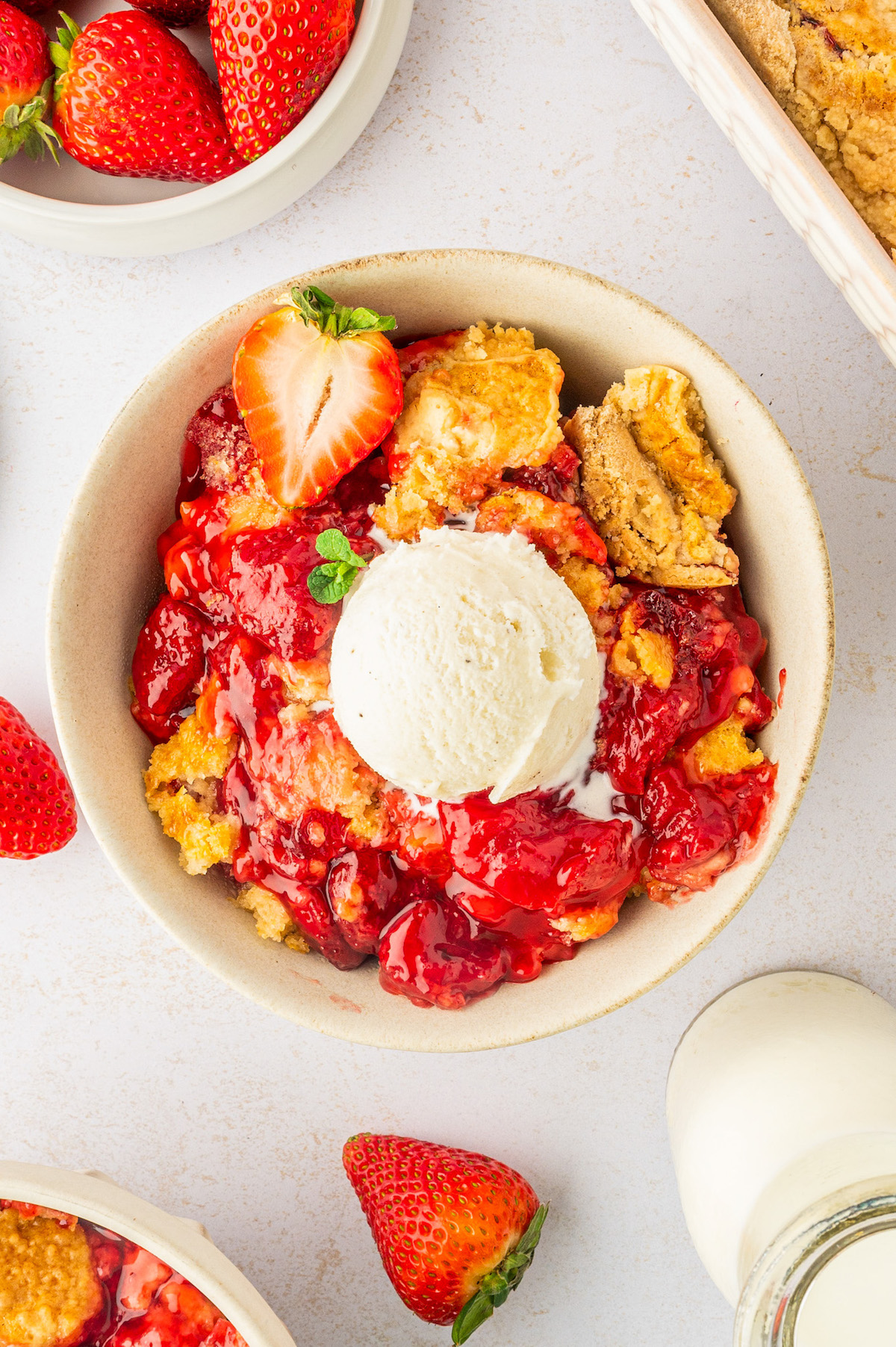 A bowl of warm strawberry dump cake with a crisp and butter topping served with a scoop of ice cream.