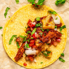 Authentic Tacos al Pastor with smoky, juicy pork, sweet grilled pineapple, salsa, diced onion and fresh cilantro.