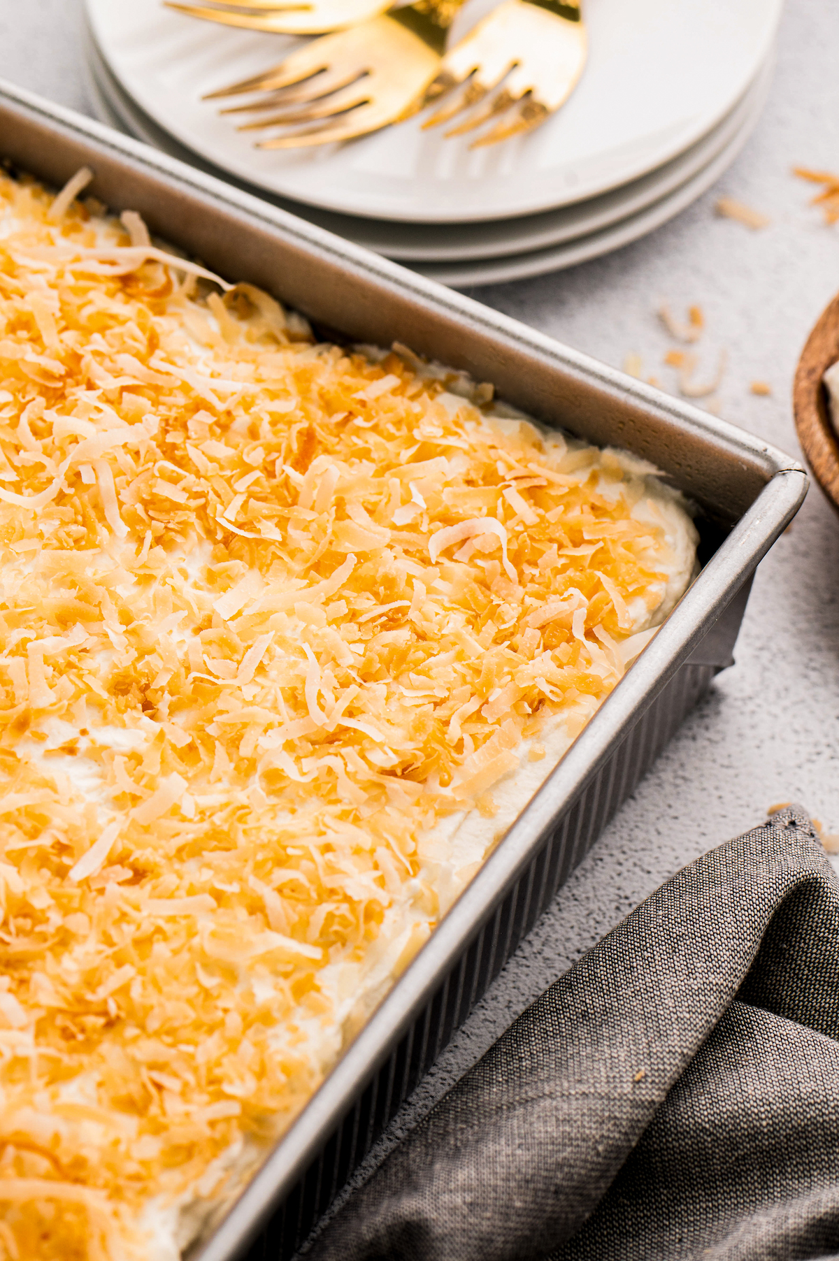 Coconut sheet cake in a baking pan topped with toasted shredded coconut.