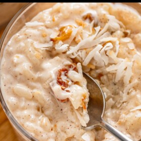 Creamy coconut rice pudding topped with toasted coconut with a spoon taking a bite.