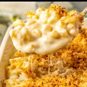 A spoonful of easy baked Mac and cheese being scooped out of a casserole dish.