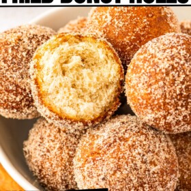 Fluffy cinnamon sugar donut holes in a bowl with a bite taken out of one.