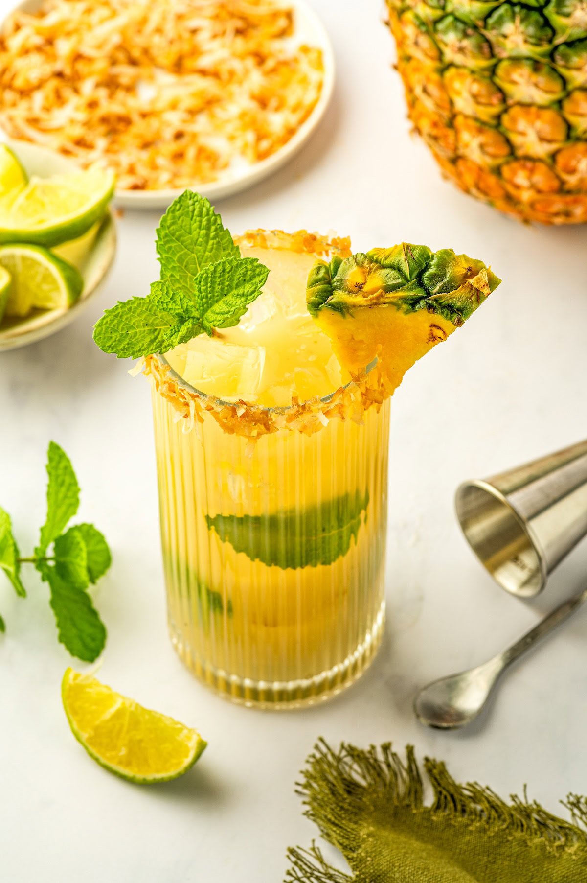 A refreshing pineapple coconut mojito with fresh mint and a toasted coconut rim.