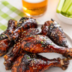 Sweet and sticky chicken drumsticks baked in a flavorful asian glaze stacked on a plate.