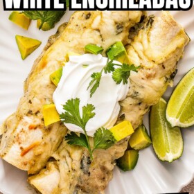 Two white chicken enchiladas with avocado on a white plate.