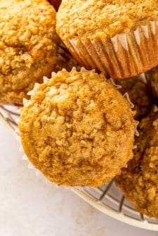Soft and warm, brown sugar banana muffins with glistening brown sugar tops are arranged in a wire basket.
