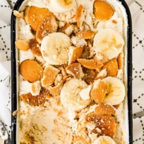 A container of banana pudding ice cream topped with nilla wafers and sliced bananas.