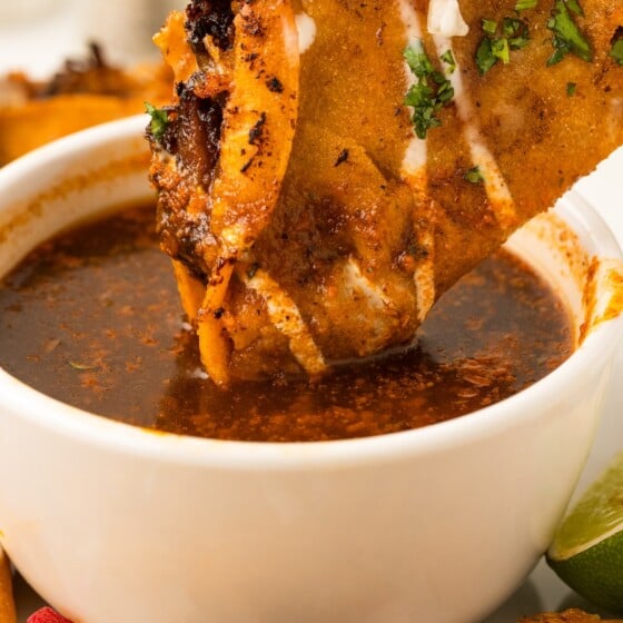 Crispy Birria Tacos being dunked in a bowl of warm birria broth.