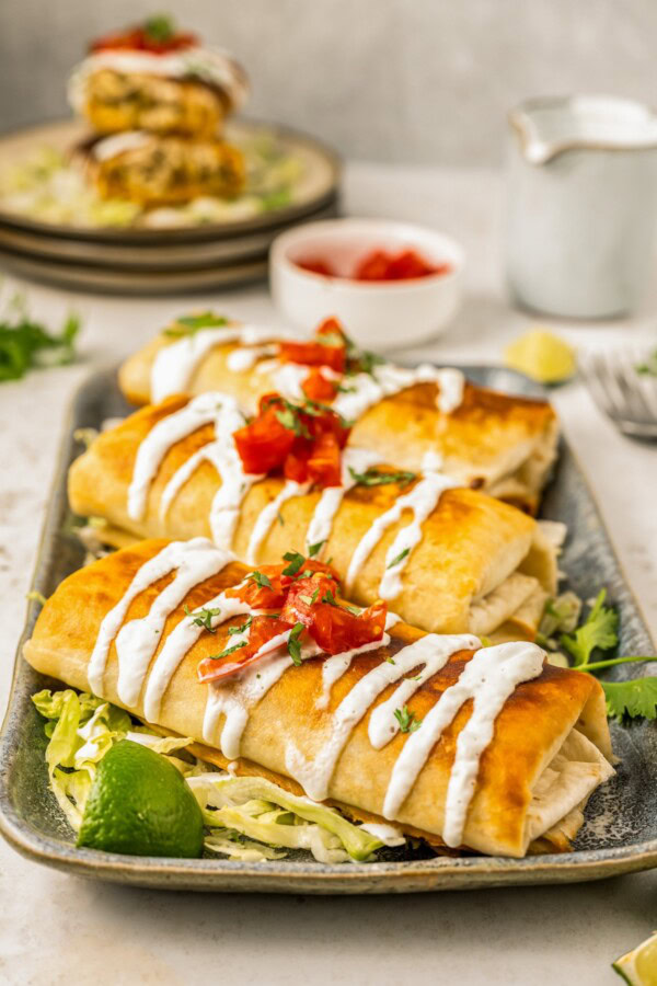 Three golden brown and crispy pan-fried chimichangas served on a platter.