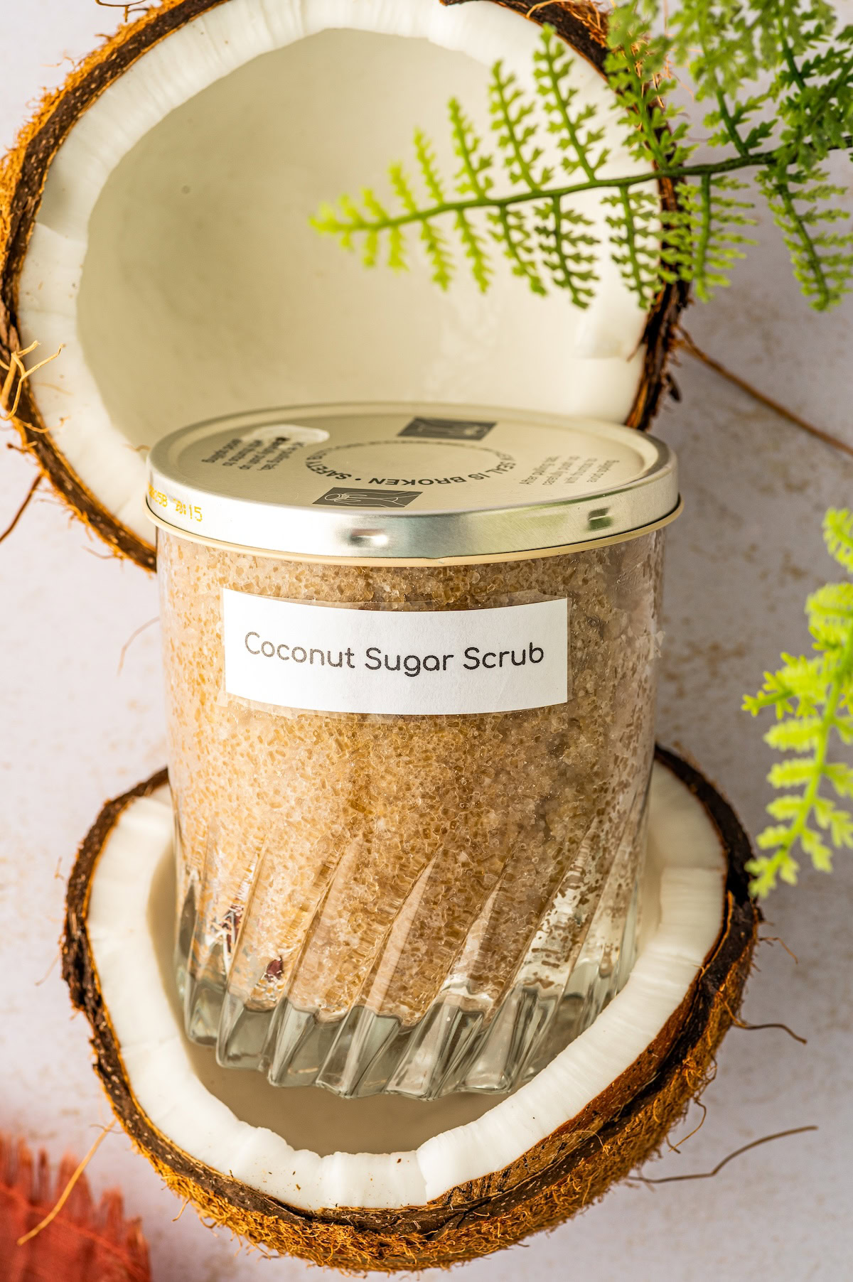 Coconut sugar scrub in a jar set inside a fresh coconut cut in half.