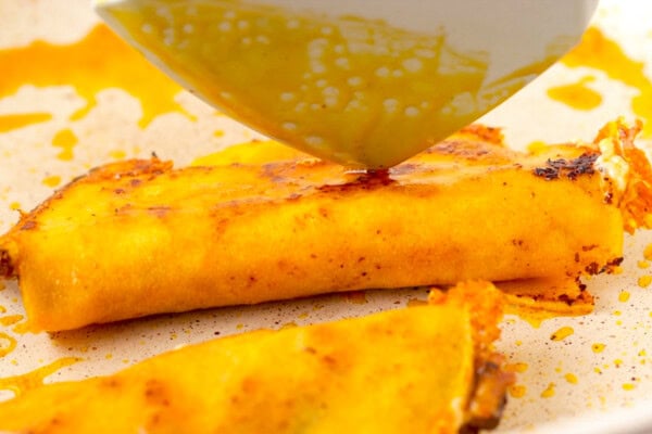 Taco being pressed in a skillet with a spatula.