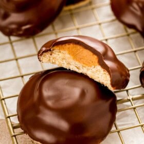 A tagalong cookie cut in half to show the layers of rich chocolate, creamy peanut butter filling and buttery shortbread cookie.