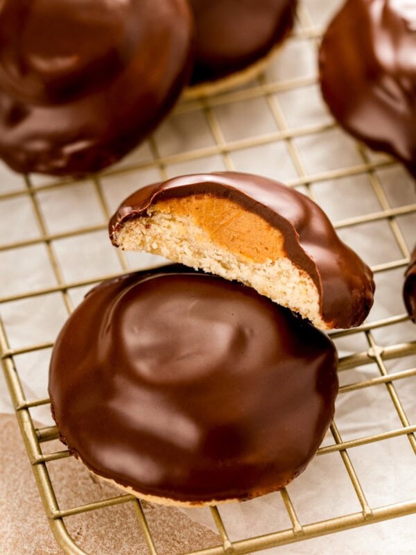 A tagalong cookie cut in half to show the layers of rich chocolate, creamy peanut butter filling and buttery shortbread cookie.