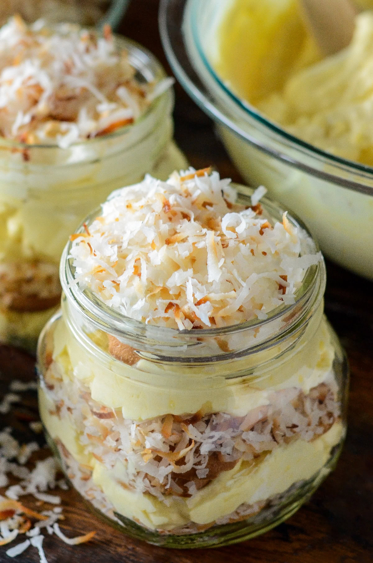 A jar of toasted coconut cream pudding with layers of vanilla wafers.