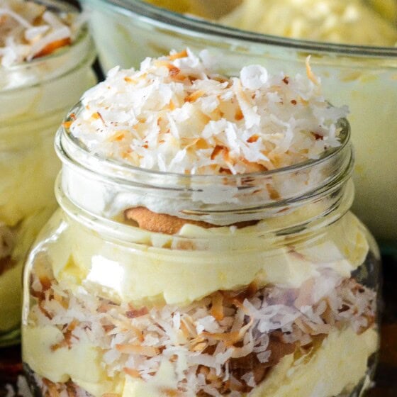 A mason jar of toasted coconut cream pudding layered with toasted coconut and vanilla wafer cookies.
