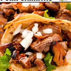 Shredded, crispy pork carnitas served as tacos in corn tortillas topped with onion and fresh cilantro.