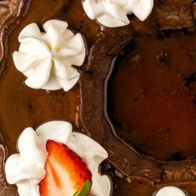 Creamy chilled chocolate flan topped with whipped cream and sliced fresh strawberries on a large serving platter.