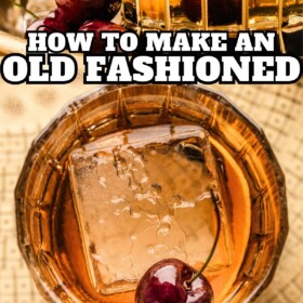 Old fashioned recipes served in a short glass with a large ice cube, orange peel and a cherry.