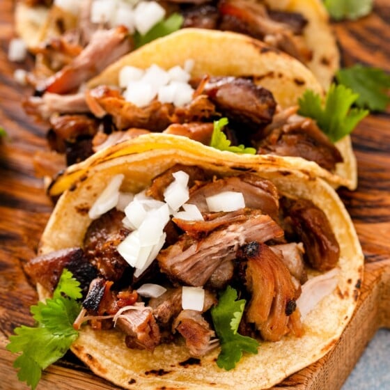 Shredded juicy pork carnitas in corn tortillas with fresh diced onion and cilantro.