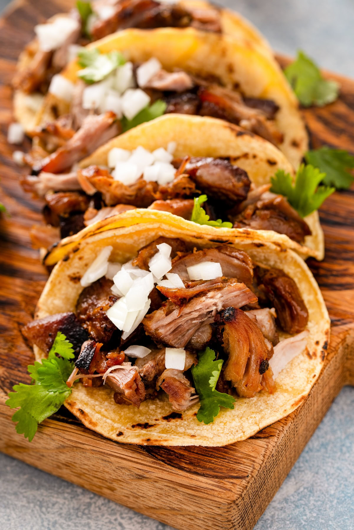 Shredded juicy pork carnitas in corn tortillas with fresh diced onion and cilantro.