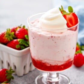 An individual serving of easy strawberry mousse with two layers of whipped pink mousse and a layer of bright red strawberry puree.