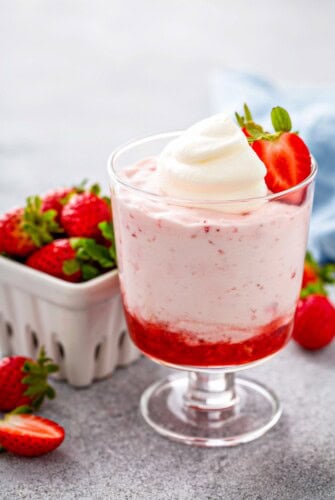 An individual serving of easy strawberry mousse with two layers of whipped pink mousse and a layer of bright red strawberry puree.