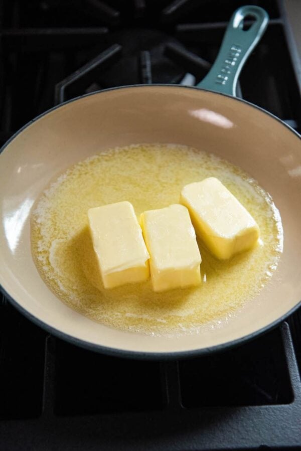 Three sticks of butter melting in a skillet.