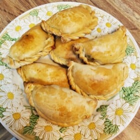 Homemade empanada dough baked into chicken empanadas and served on a large platter.