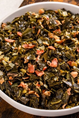 Tender collard greens simmered in beer with crispy bacon in a serving bowl.