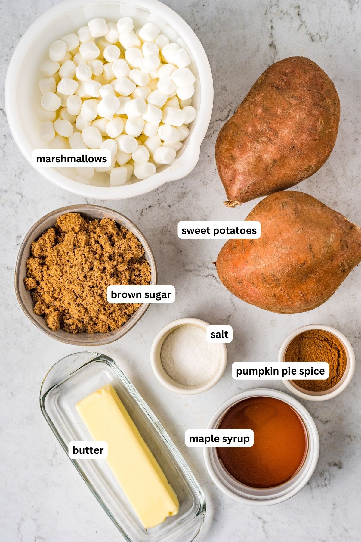 Ingredients for crockpot sweet potatoes recipe arranged in bowls. From top to bottom: sweet potatoes, mini marshmallows, brown sugar, butter, salt, pumpkin pie spice, maple syrup, mini marshmallows, and cinnamon.