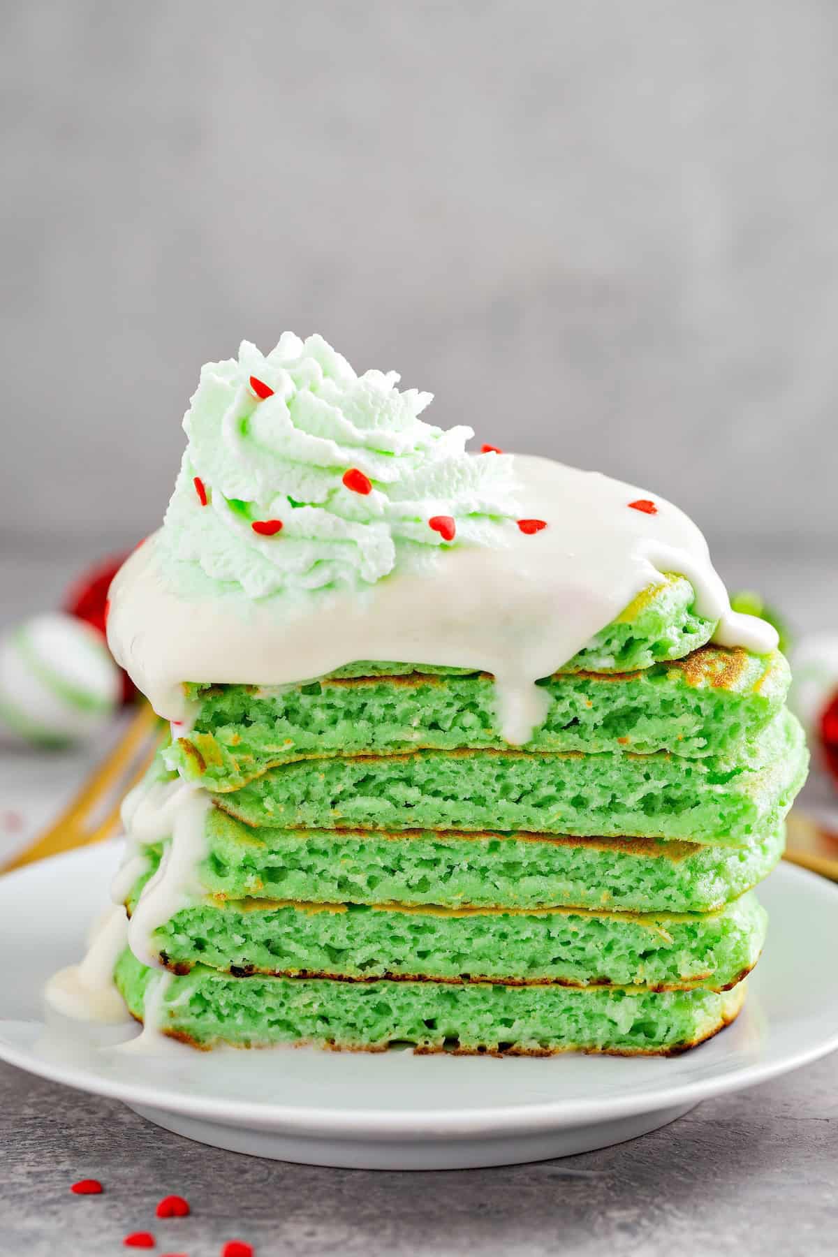 A stack of green grinch pancakes cut in half to show the fluffy centers.