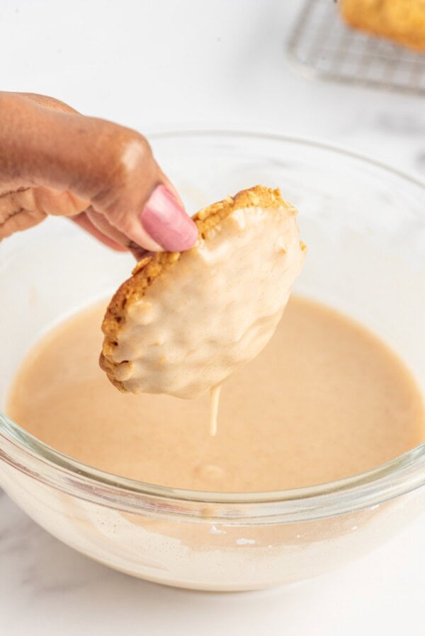 A soft oatmeal pumpkin cookie has been dipped into smooth, sweet cinnamon icing.