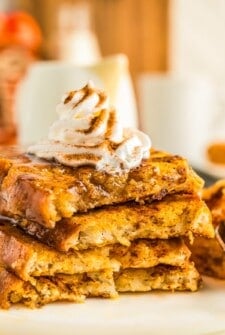 Piped whipped cream on top of a stack of fluffy pumpkin spice French toast.