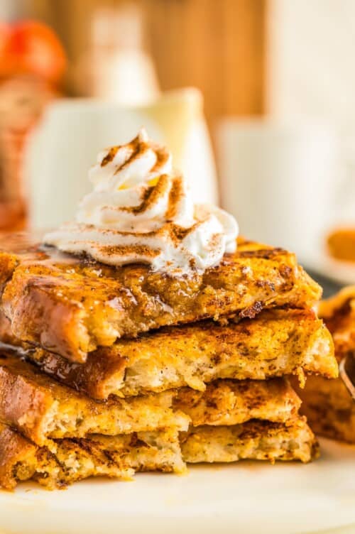 Piped whipped cream on top of a stack of fluffy pumpkin spice French toast.