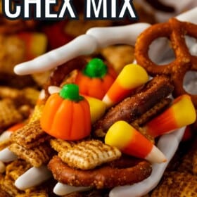 A skeleton hand holding a handful of halloween Chex mix with candy corn.