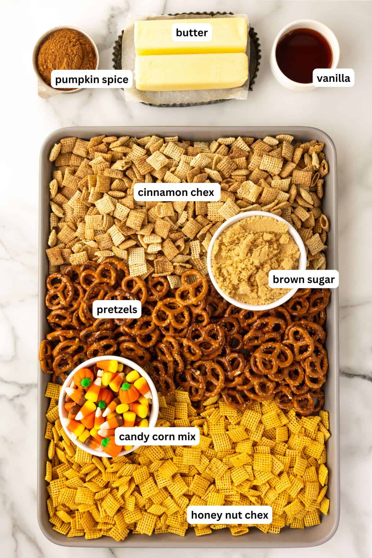 Ingredients for halloween chex mix recipe in order from top to bottom: pumpkin spice, butter, vanilla, cinnamon chex, brown sugar, pretzels, harvest candy mix, honey nut chex.