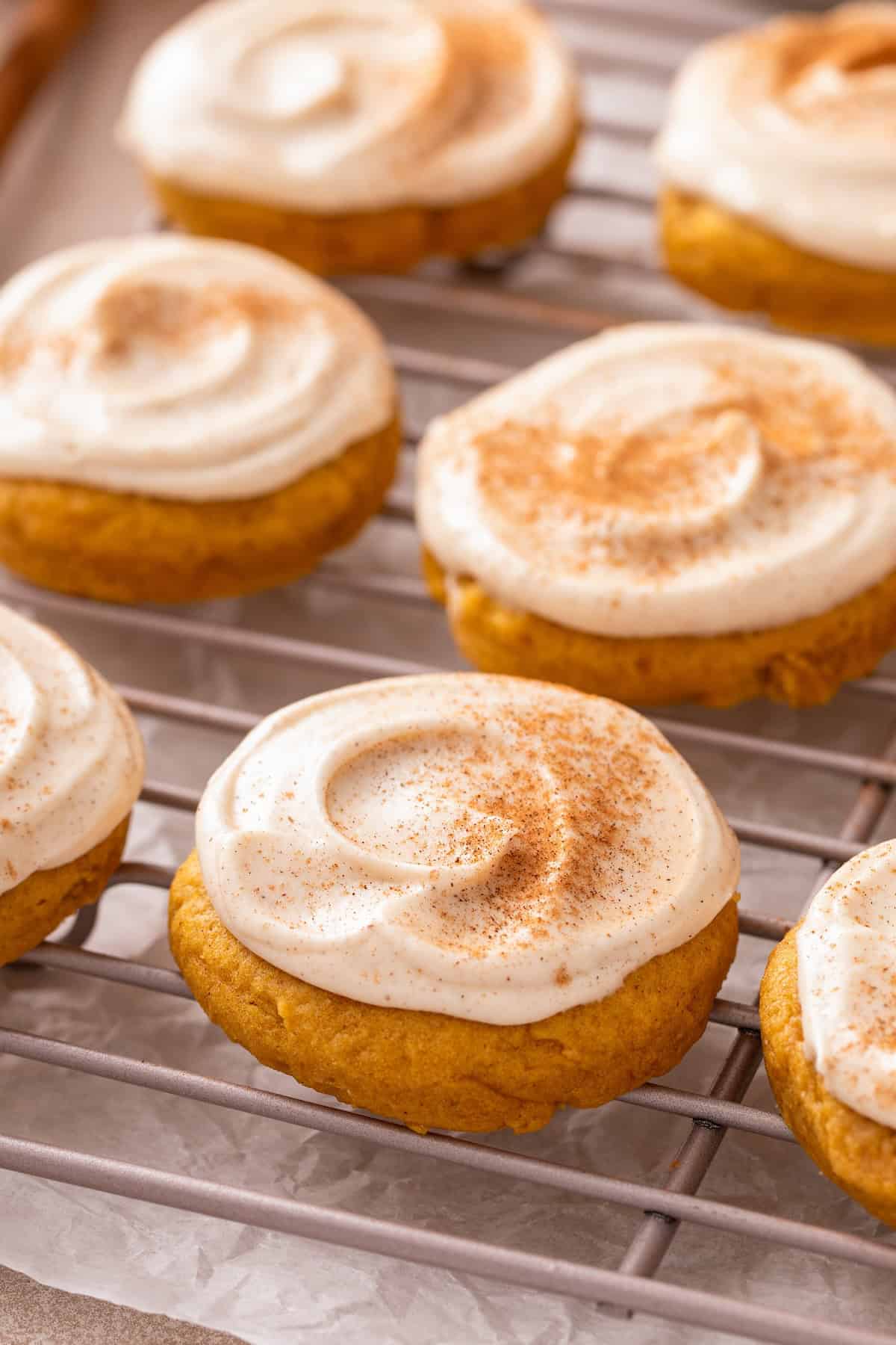 Soft pumpkin cream cheese cookies with cinnamon dusted on top set on a metal cooling rack.