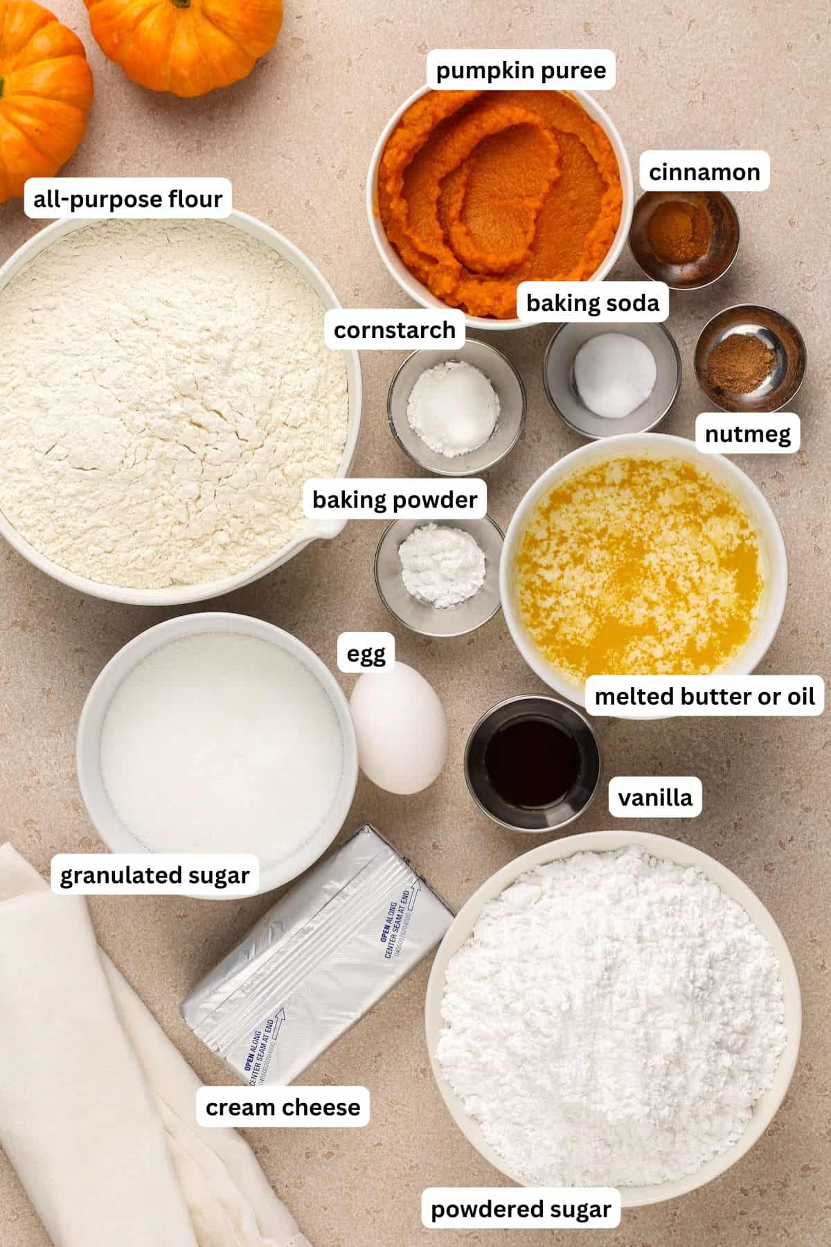 The ingredients for soft pumpkin cookie recipe in order from top to bottom: all purpose flour, pumpkin puree, cinnamon, nutmeg, baking soda, cornstarch, baking soda, melted butter, egg, vanilla, granulated sugar, cream cheese, powdered sugar.