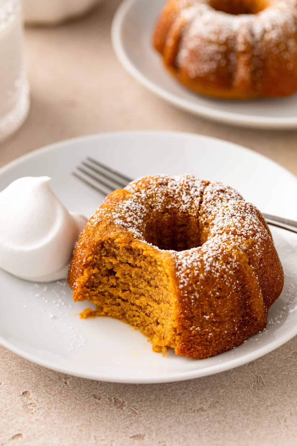 A bite has been taken out of a moist mini pumpkin bundt cake dusted with powdered sugar. 