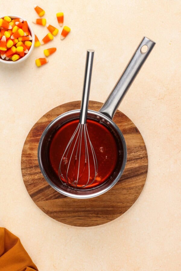 Candy corn simple syrup being whisked in a pot.