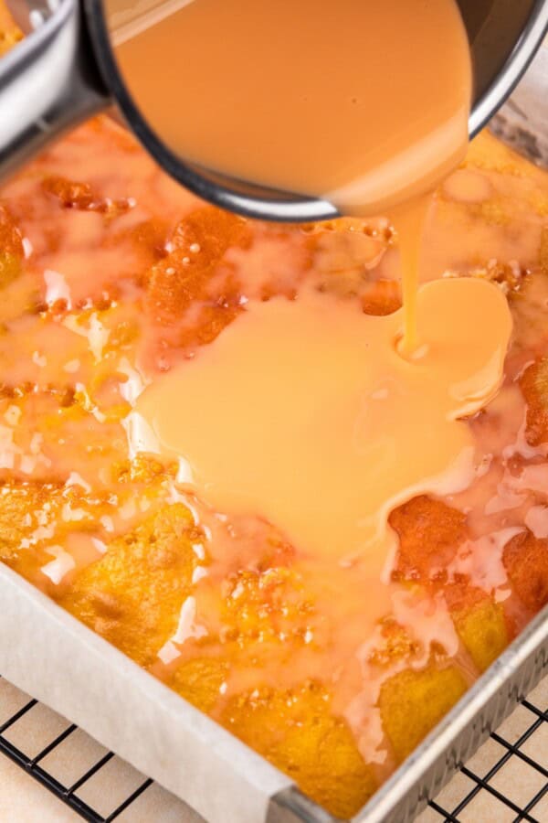 A creamy mixture poured all over the top of a baked cake.